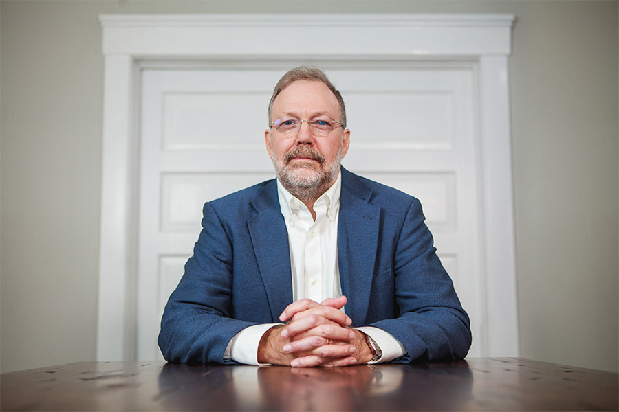 Dr. Nicholas Meriwether is pictured sitting at a desk with his hands crossed